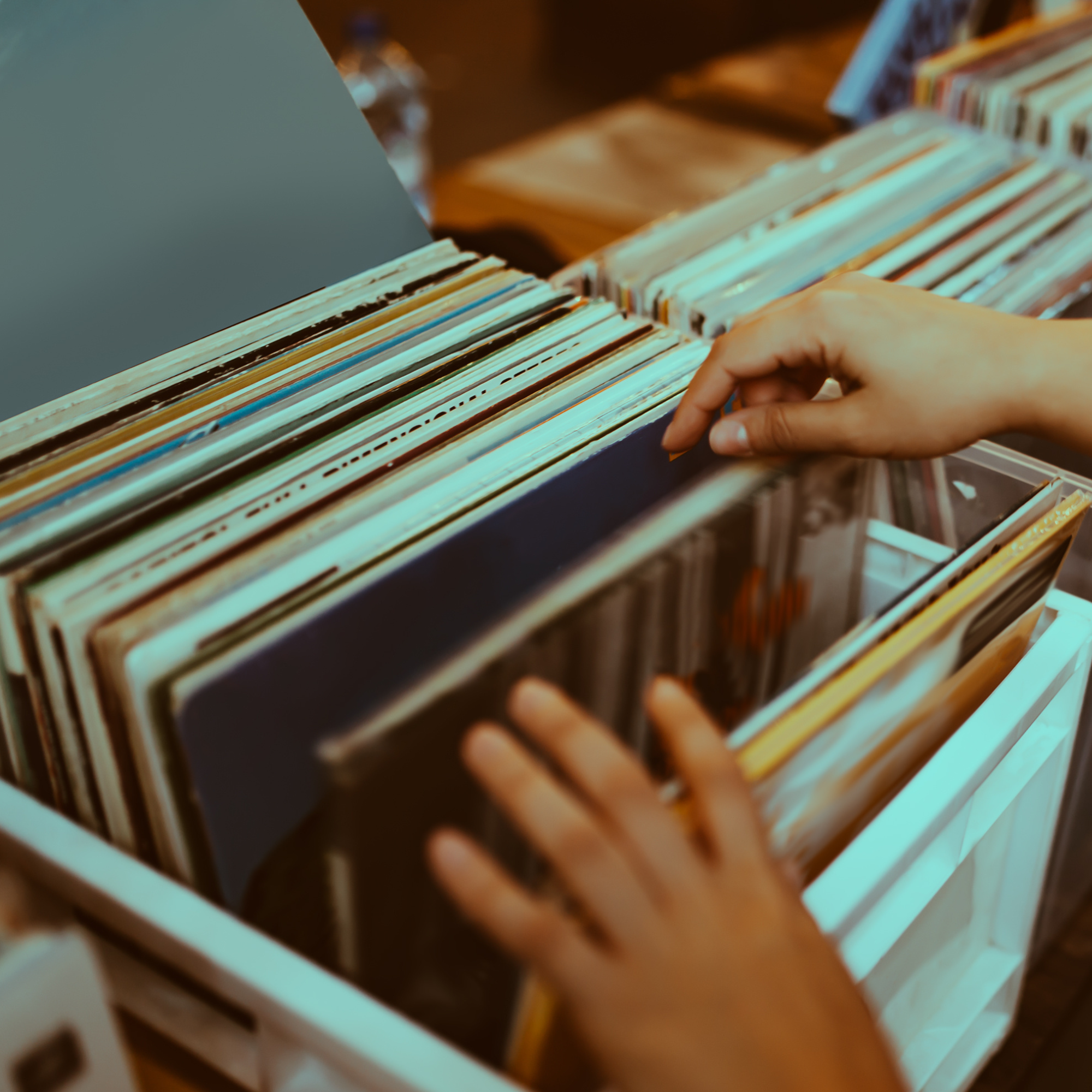 A person flicking through a box of vinyl records