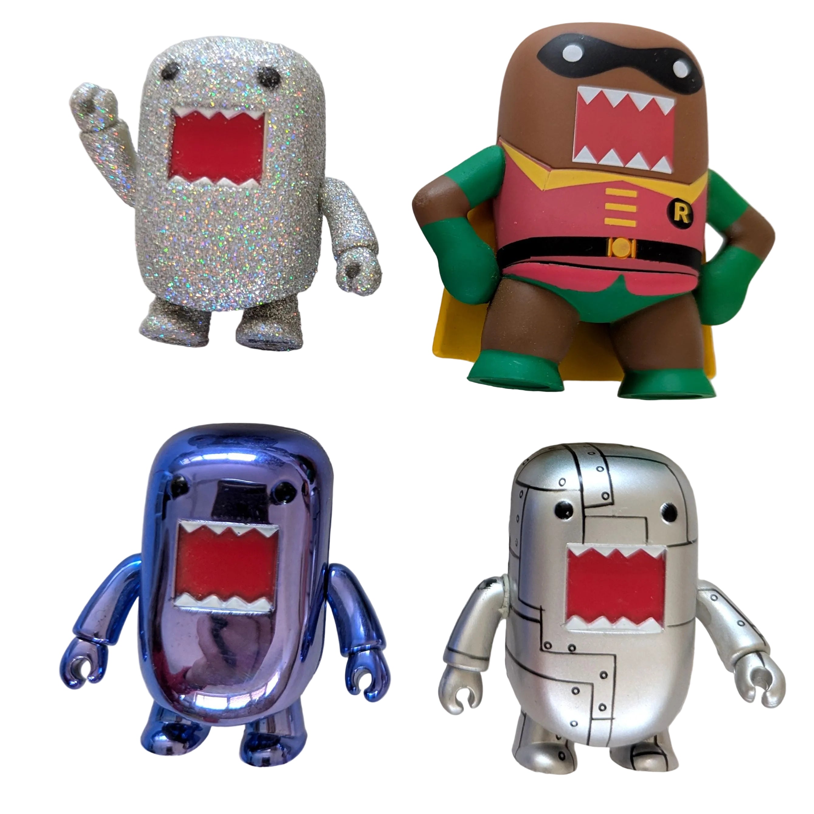 Four stylized character figurines arranged in a 2x2 grid on a light beige surface. The top-left figure is silver glitter with a red mouth; the top-right figure resembles a superhero with brown skin, green and red costume, and yellow cape; the bottom-left figure is shiny metallic purple-blue; the bottom-right figure is silver with a red mouth.