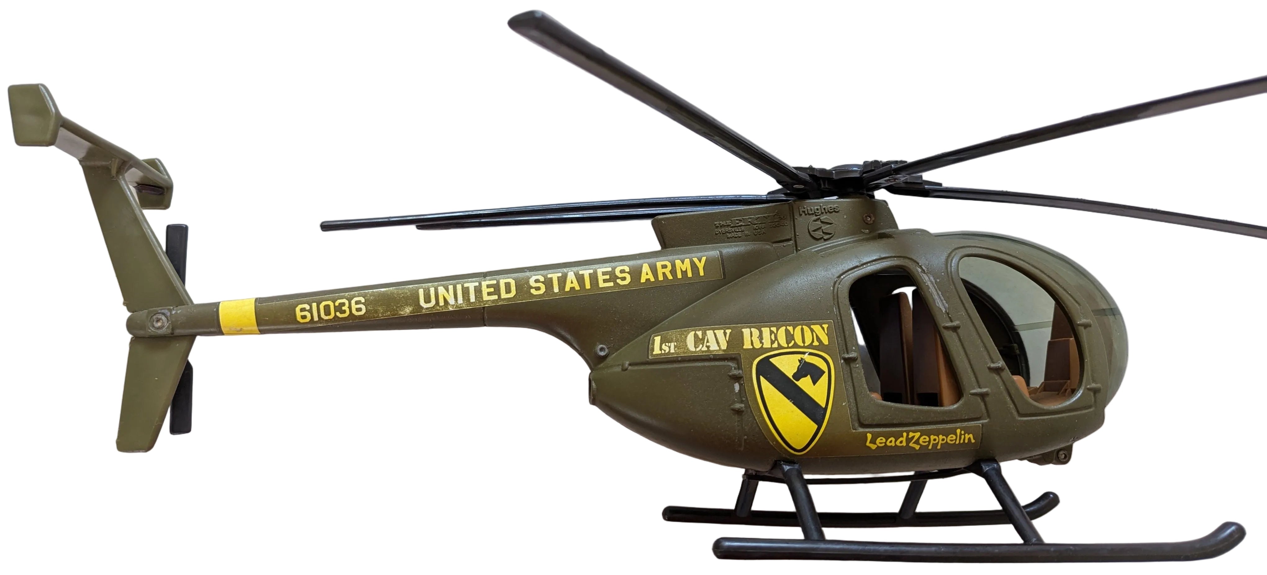 A toy military helicopter in olive green with yellow and black markings, featuring 'UNITED STATES ARMY' and '1st CAV RECON' text, photographed against a light gray background.