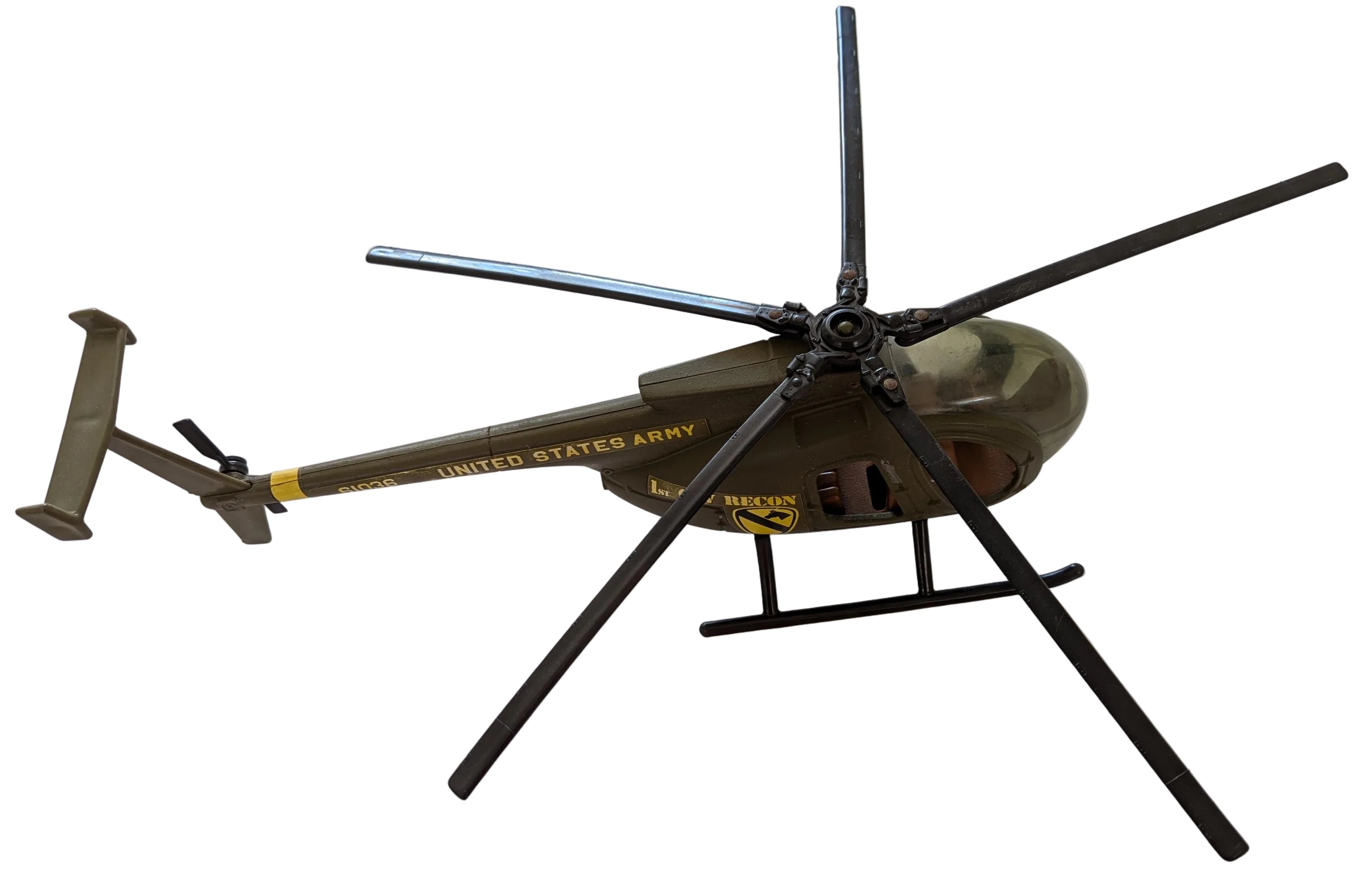 A vintage military-style helicopter model or toy on a white cardboard background, featuring olive green and black colors with yellow 'United States Army' text.