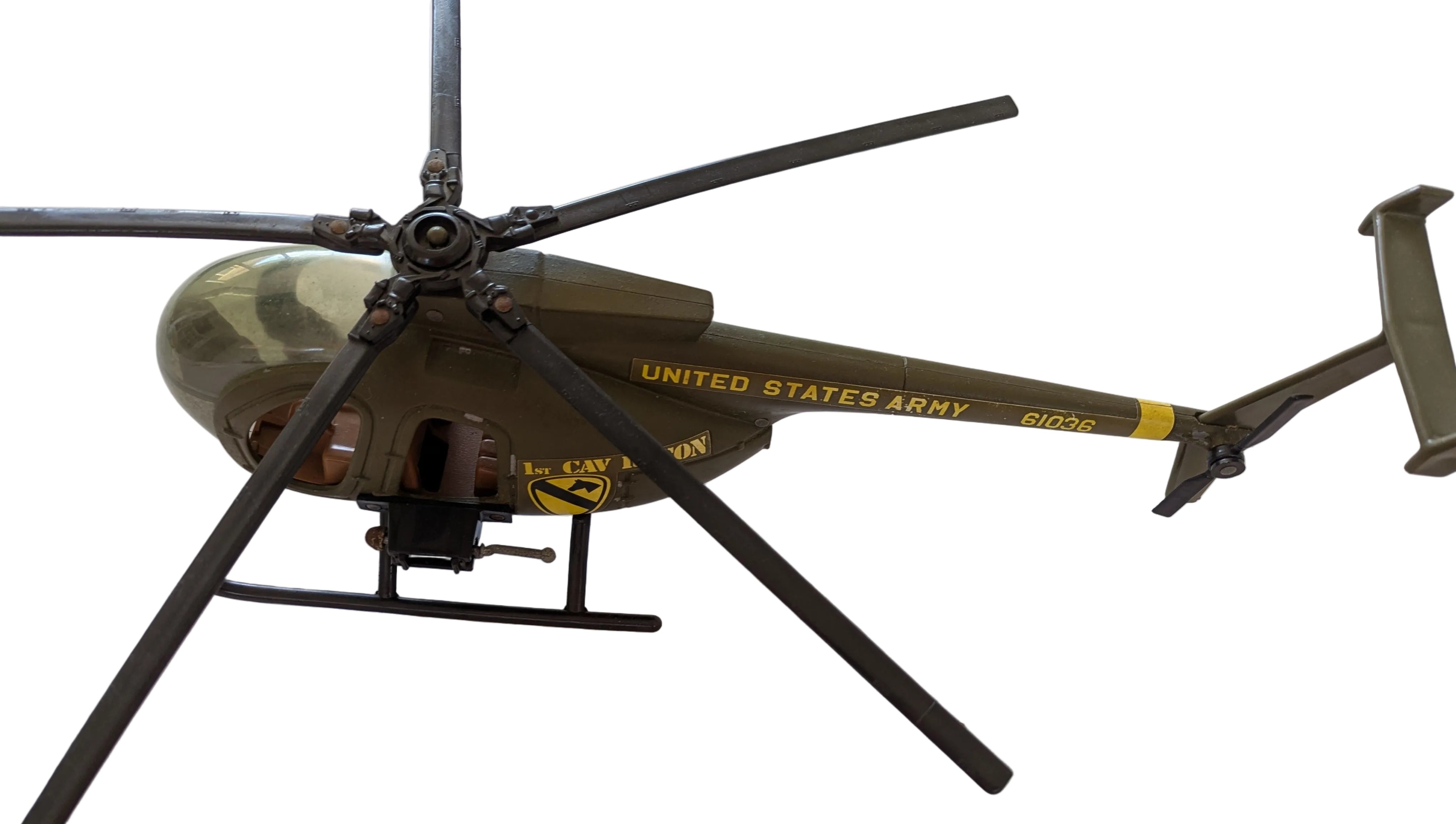 A scale model of a United States Army Bell 206 helicopter in olive drab green and black, featuring yellow printed text and insignia, photographed from an overhead angle on a white background.