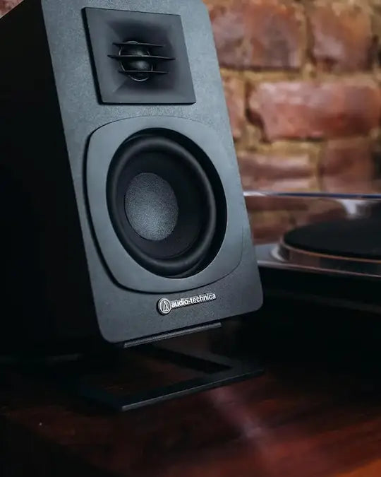 Black Speaker sitting on table beside turntable