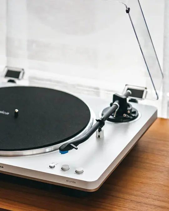 White turntable on a wooden surface with a white background