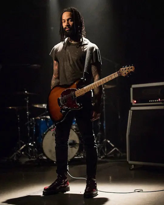 Person playing guitar on stage with musical equipment in the background