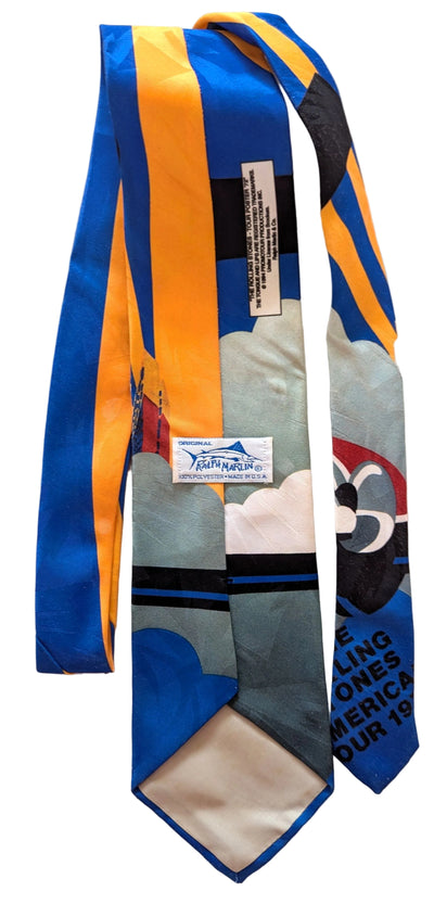 A vintage necktie featuring a colorful abstract design with blue, yellow, gray, black, and white sections, along with printed text and a small brand label.