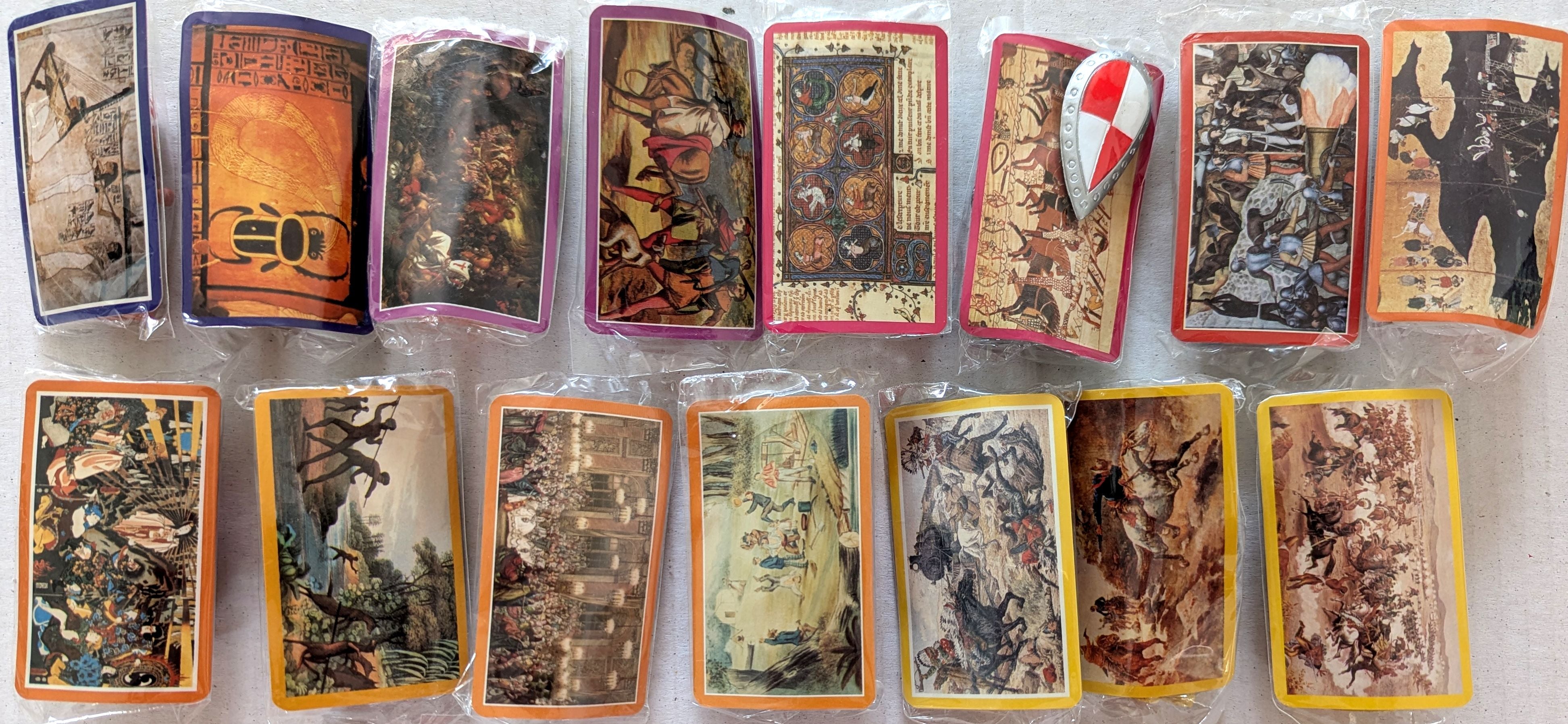 A set of illustrated collector cards arranged in two rows on a light surface. The cards feature various fantasy and historical scenes with colorful borders in orange, yellow, red, purple, and blue.
