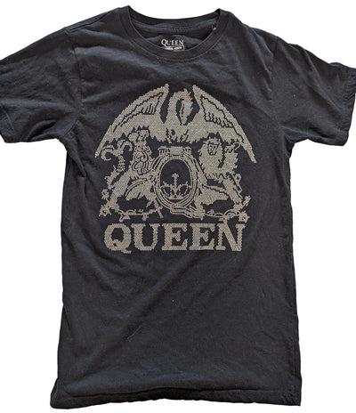 A black short-sleeve Queen band t-shirt featuring the band's logo and 'QUEEN' text in a distressed, pixelated silver graphic on the front, laid flat on a light wood background.