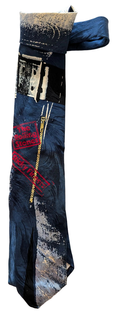 A dark blue necktie with an abstract black, white, and gray brushstroke pattern and a red graphic print, laid flat on a light beige textured background.