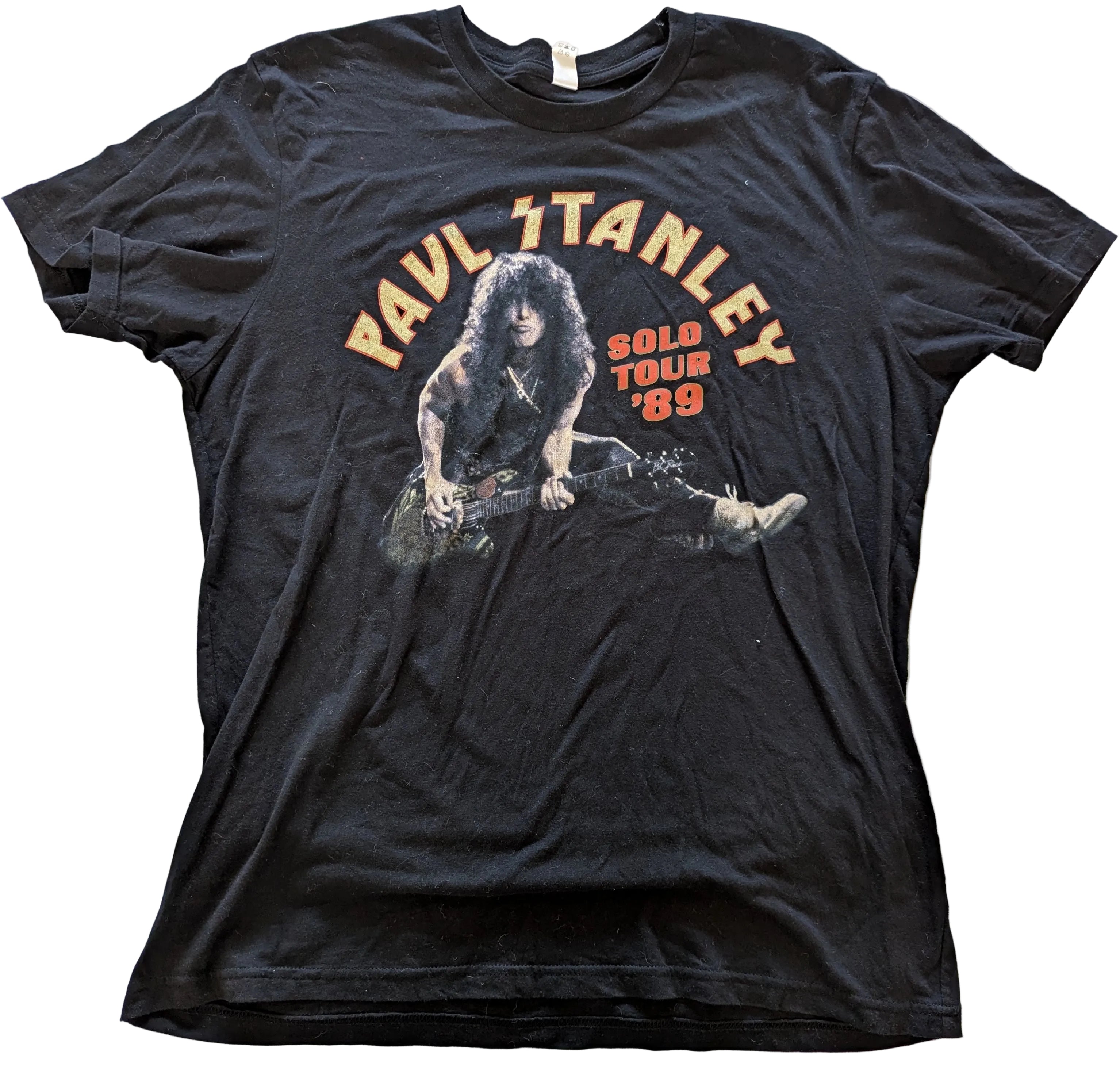 Black t-shirt with graphic of a person playing guitar and text 'Paul Stanley Solo Tour '89' on a white background