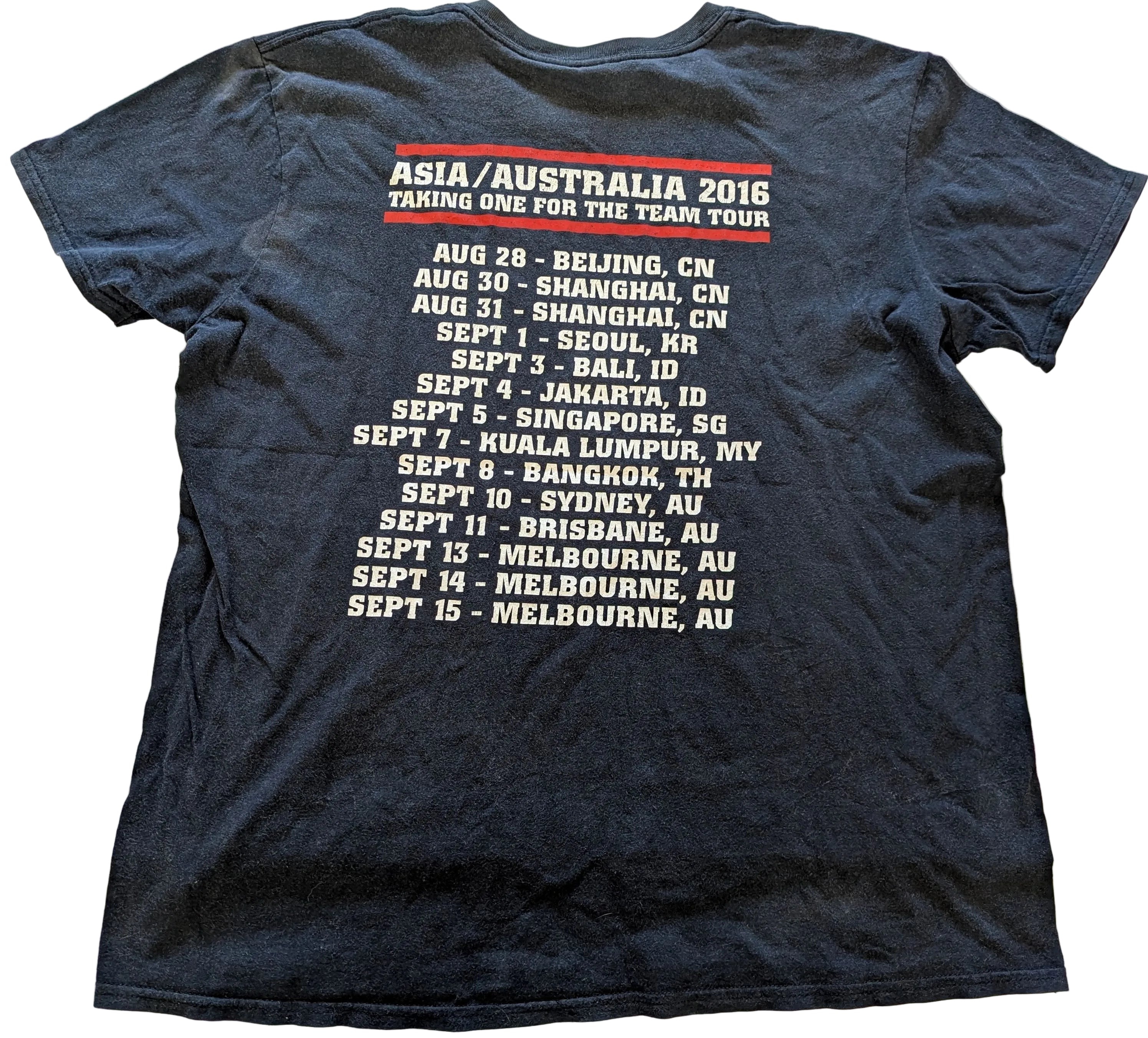 Black t-shirt with concert tour dates on the back, displayed on a white surface.